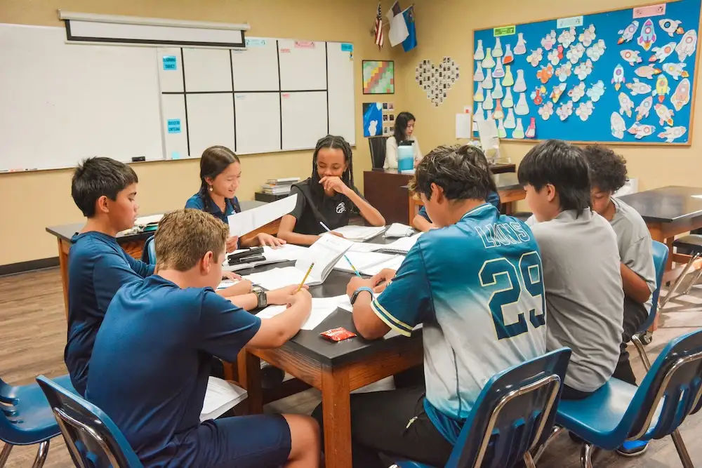 Middle school students working together around tables in a classroom